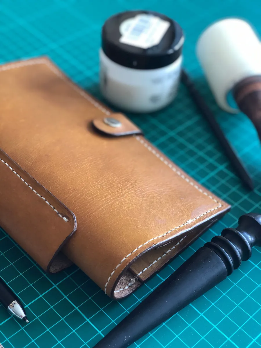Leather wallet and craft tools on a green cutting mat