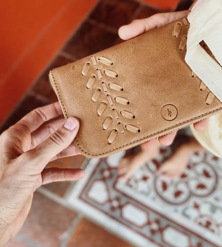 Hands presenting a decorated handmade leather wallet