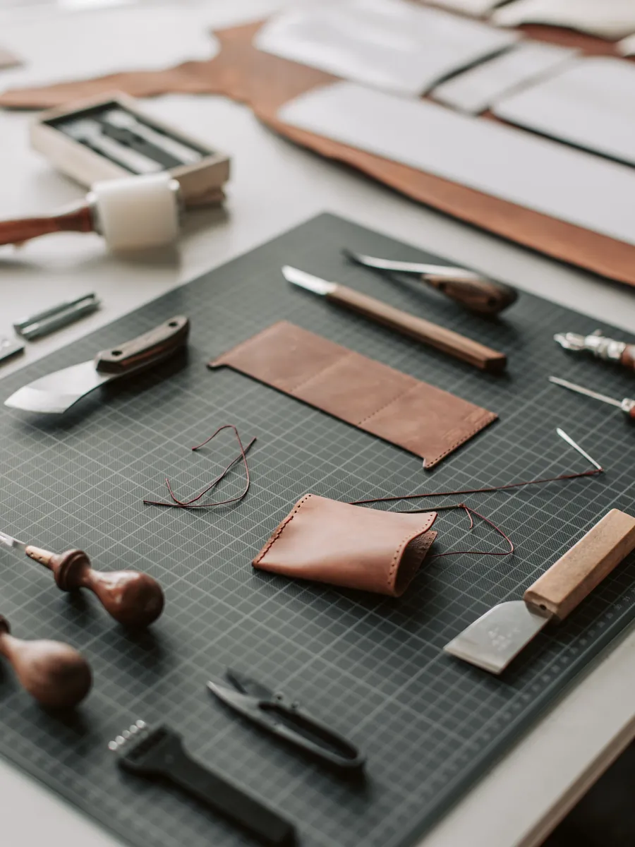 Leather pieces and tools spread across a working studio desk
