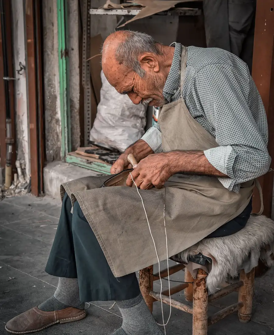 Experienced craftsperson hand-stitching leather in a traditional workshop