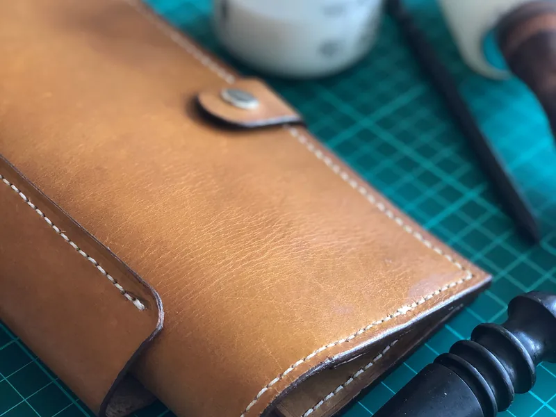 Finished leather wallet beside precision craft tools