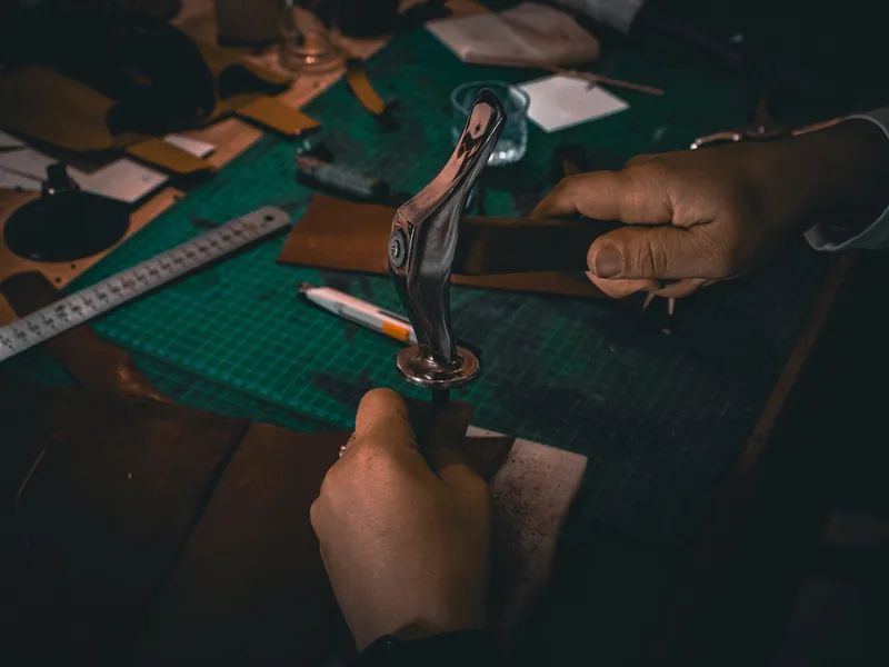 Hands punching stitching holes into a leather strap