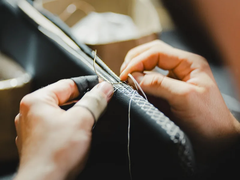 Artisan hand-stitching leather with needle and thread