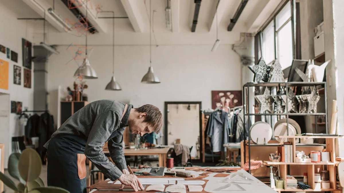 Leatherworker cutting a pattern from a sheet of brown leather
