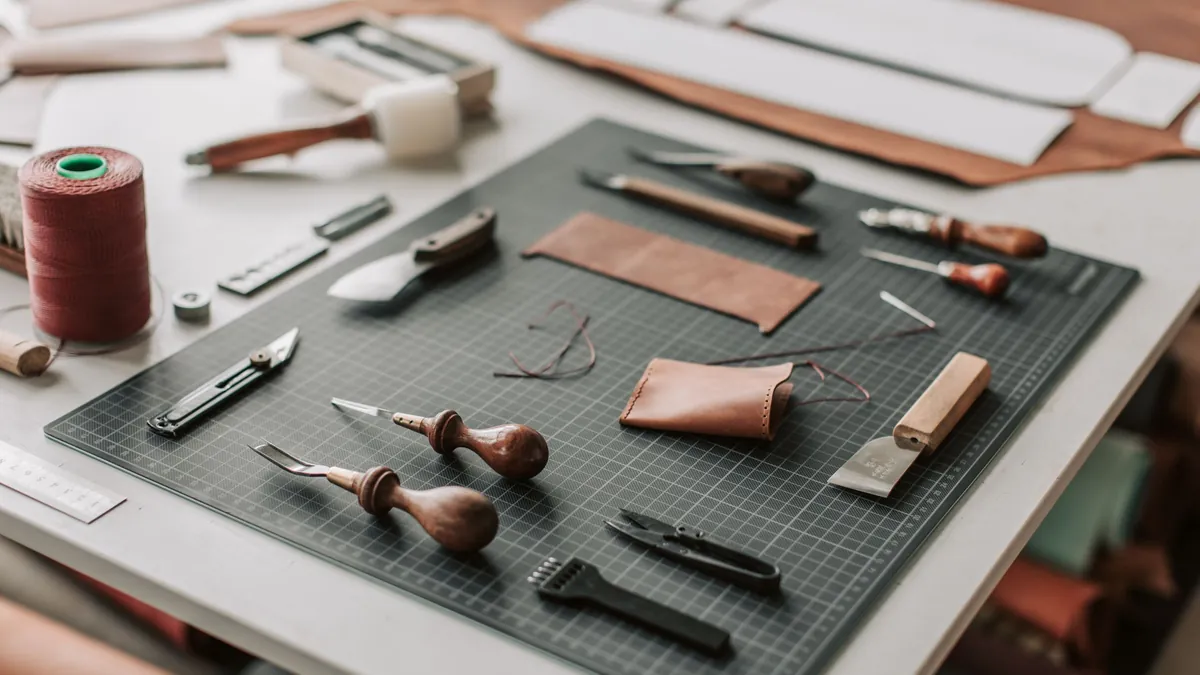 Essential leatherworking hand tools arranged on a cutting mat